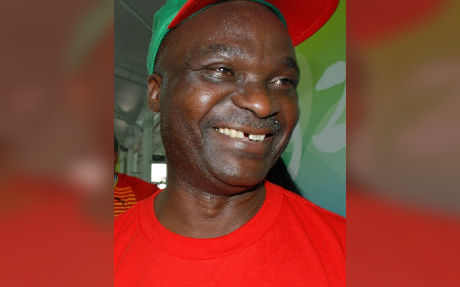 Man in a red and green cap and red shirt smiling broadly